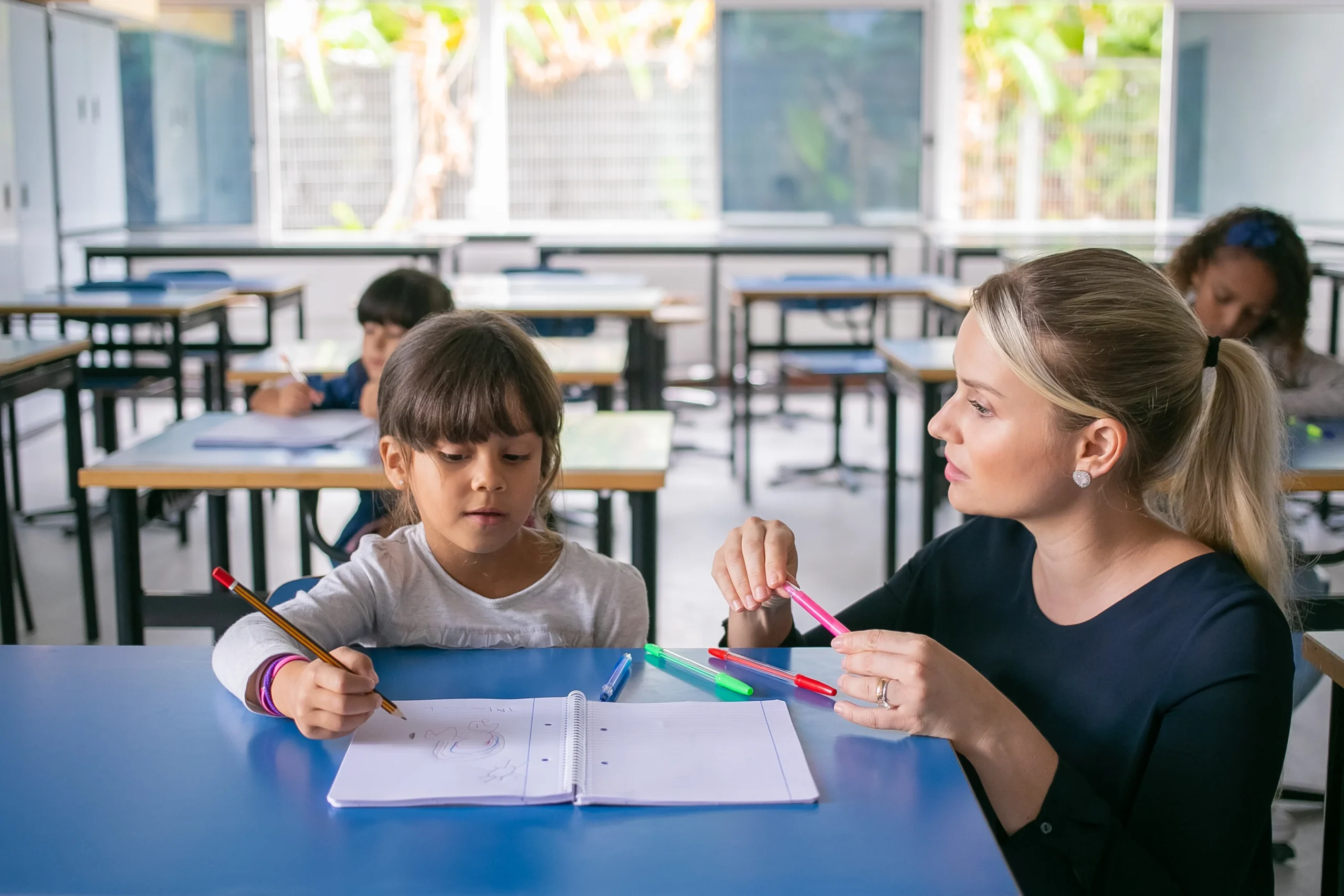 serious-primary-school-teacher-helping-girl-cope-with-her-task